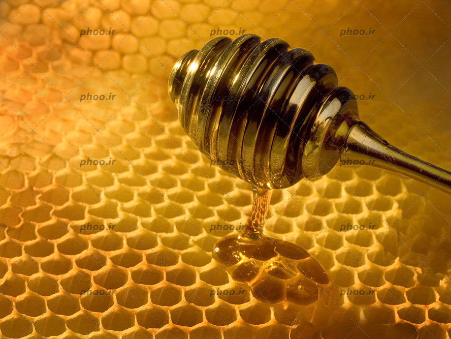 عکس با کیفیت قاشق فلزی عسل در حال برداشتن عسل از موم عسل تازه