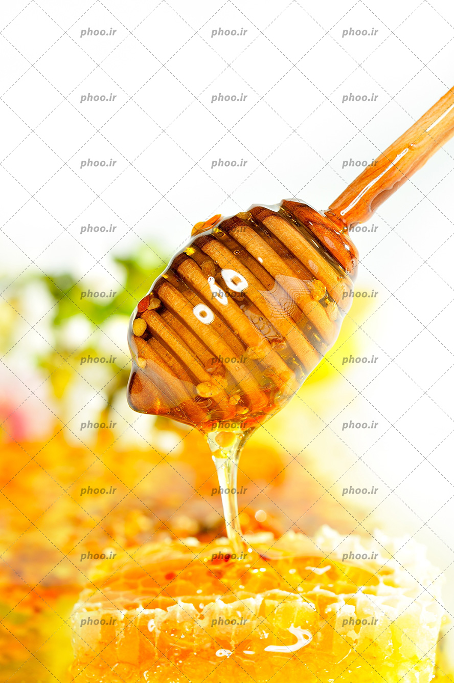 عکس با کیفیت عسل در حال ریخته شدن از قاشق چوبی عسل بر روی موم عسل تازه