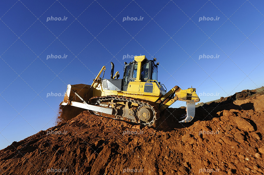 عکس با کیفیت بیل مکانیکی به رنگ زرد و در حال کندن و گود برداری زمین