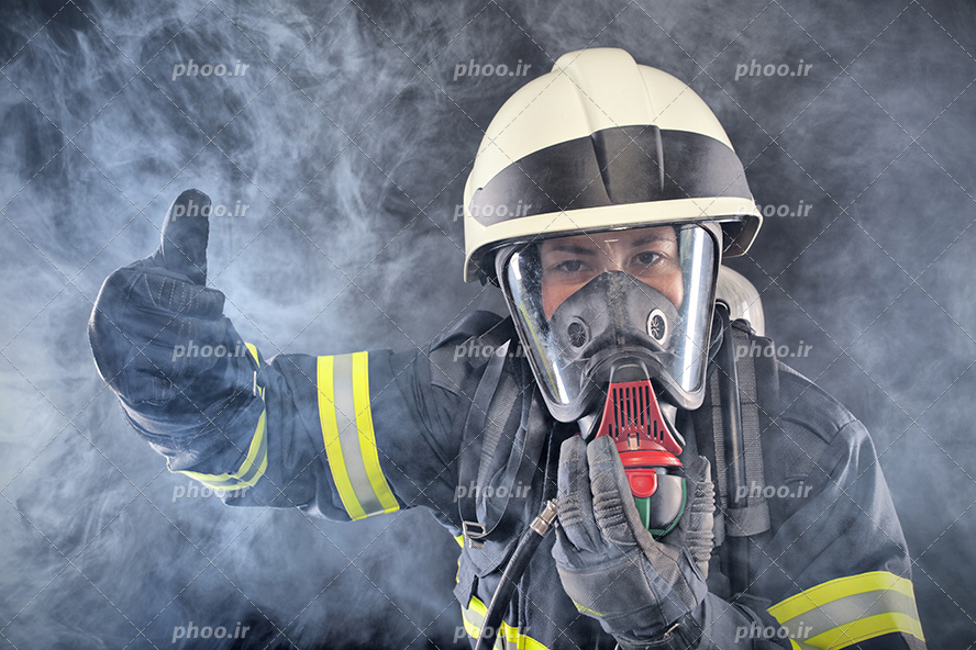 عکس با کیفیت آتشنشان با ماسک اکسیژن بر روی صورت و آتشنشان در دود و تاریکی