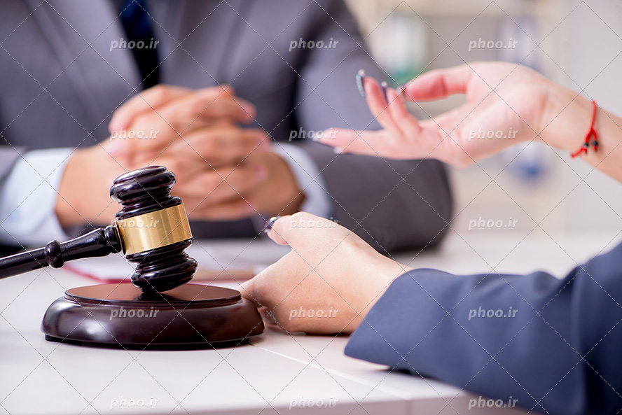 عکس با کیفیت موکل در حال توضیح مشکلات خود به وکیل خود و چکش عدالت بر روی میز