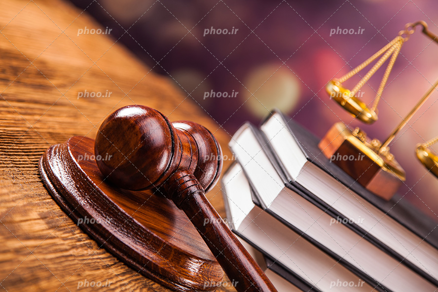 عکس با کیفیت ترازو عدالت بر روی کتاب های قانون و چکش عدالت در کنارش بر روی میز چوبی