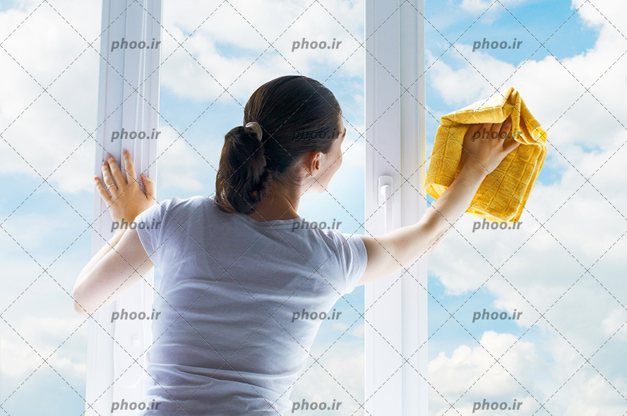 عکس با کیفیت زن نظافتچی در حال تمیز کردن شیشه های بزرگ ساختمان و آسمان آبی