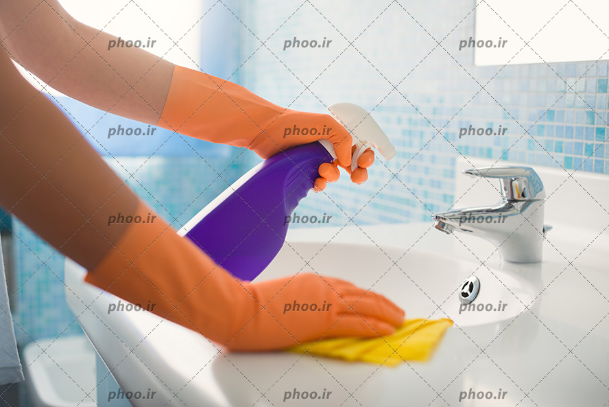 عکس با کیفیت نظافتچی با دستکش در حال تمیز کردن روشویی با مواد شوینده