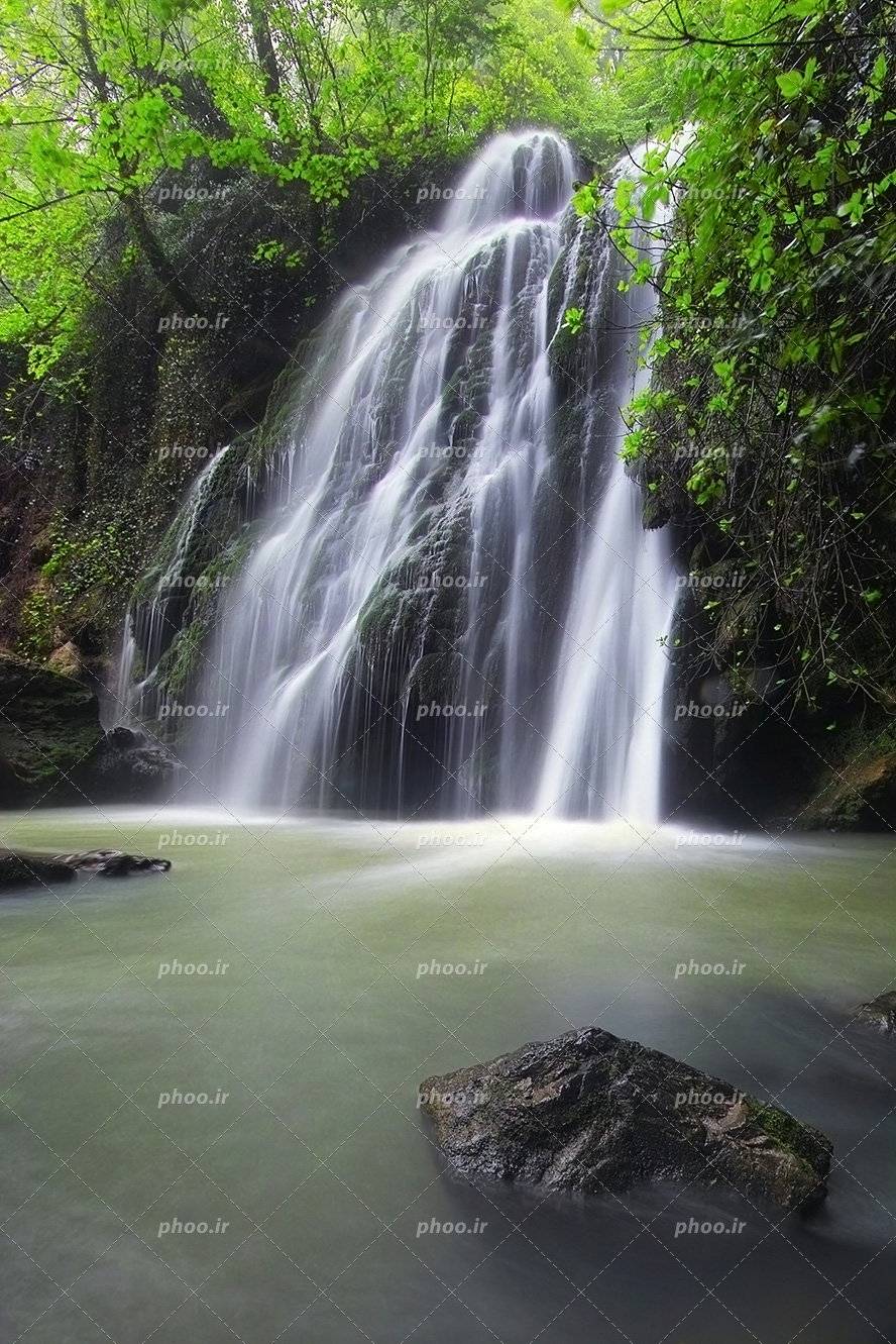 عکس با کیفیت آبشار در دل جنگل و جنگل سرسبز و سنگ های بزرگ در رودخانه
