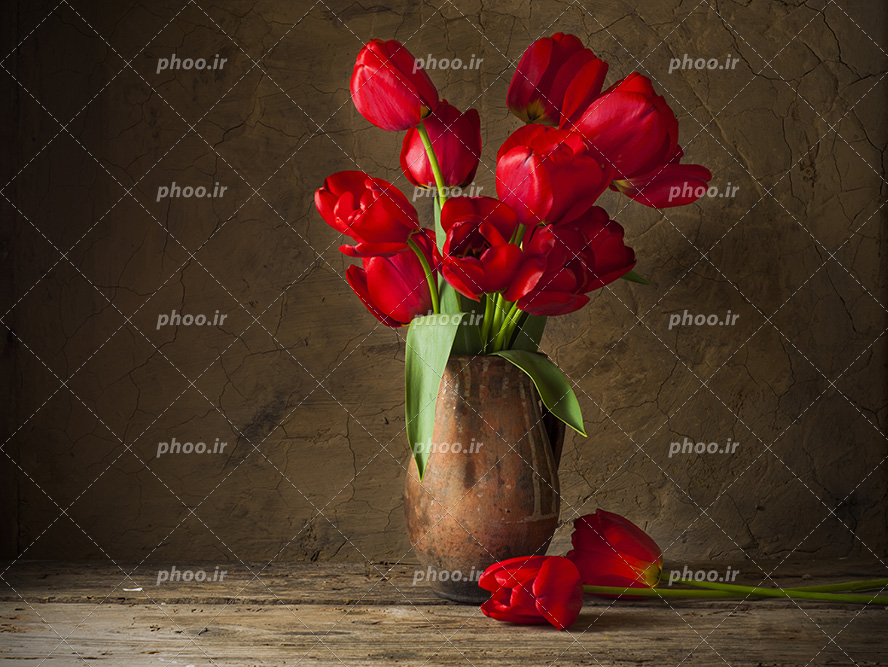 عکس با کیفیت گل های لاله ی قرمز داخل گلدان چوبی و قرار گرفته بر روی میز چوبی