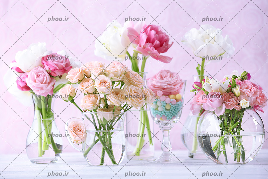 عکس با کیفیت گل های رز زیبا در رنگ های مختلف در گلدون های شیشه ای و پس زمینه به رنگ صورتی