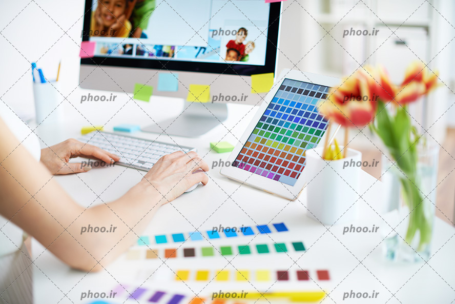 عکس با کیفیت زن در حال کار کردن با سیستم و چند جدول رنگ بر روی میز