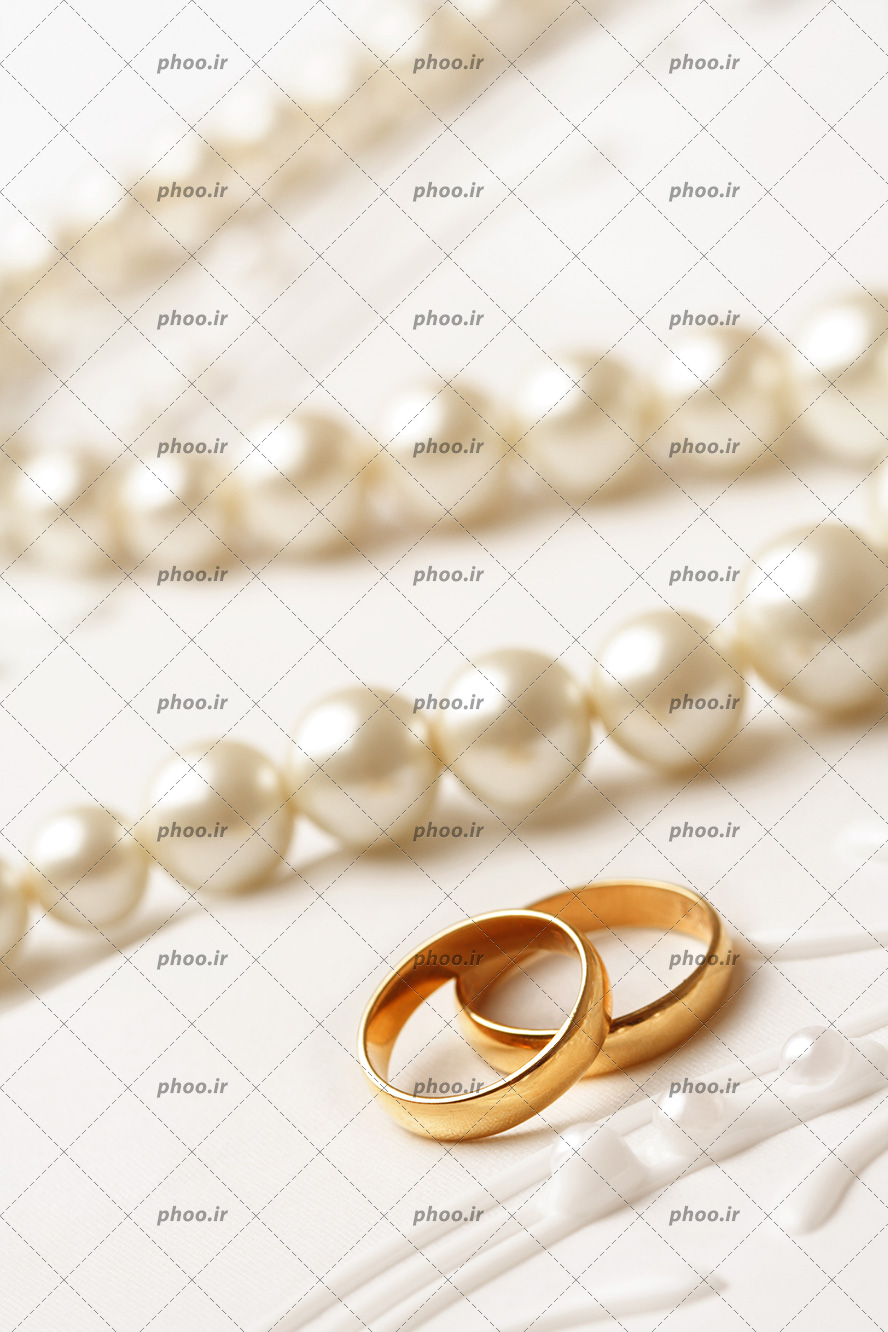عکس با کیفیت دو حلقه ازدواج طلایی ساده در کنار گردنبند مروارید