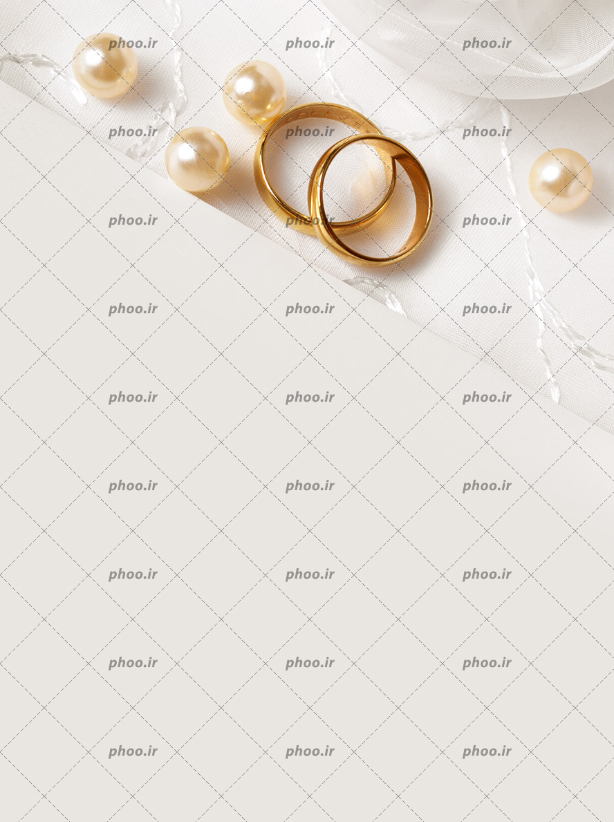 عکس با کیفیت دو حلقه طلایی بر روی کاغذ سفید و چند مروارید طلایی رنگ در اطراف