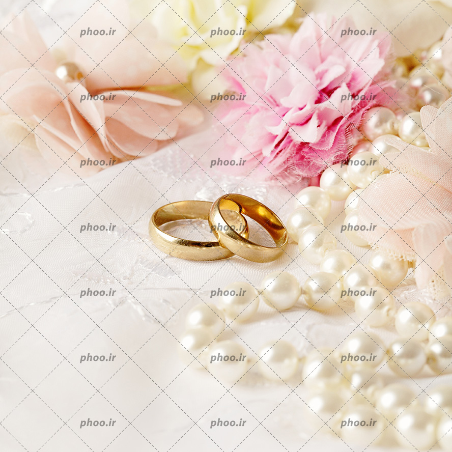 عکس با کیفیت دو حلقه ی ازدواج در کنار گل های صورتی و گردنبند مروارید