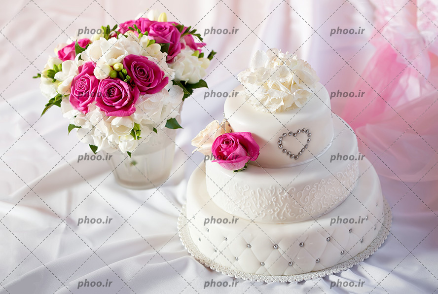 عکس با کیفیت کیک سه طبقه در کنار گلدان زیبا بر روی پارچه ی ساتن