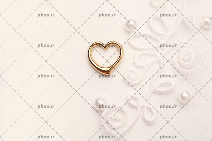 عکس با کیفیت پارچه گلدوزی شده و حلقه ای طلایی به شکل قلب بر روی پارچه