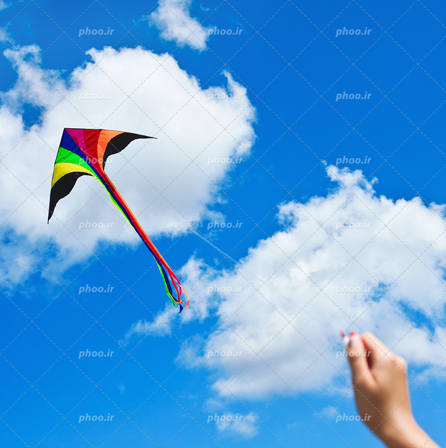 عکس با کیفیت کودک در حال بازی با بادبادک در آسمان آبی ابری