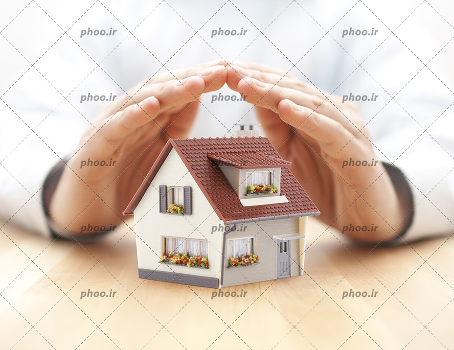 عکس با کیفیت دستان مرد به صورت سقف قرار گرفته بر روی ماکت خانه ی زیبا