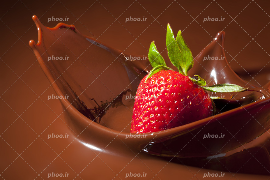 عکس با کیفیت سقوط توت فرنگی قرمز داخل شکلات ها و پخش شدن شکلات ها در هوا