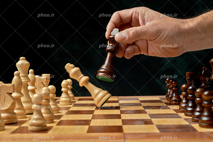 عکس با کیفیت مرد در حال بازی شطرنج و حذف کردن مهره بازی حریف از نمای نزدیک