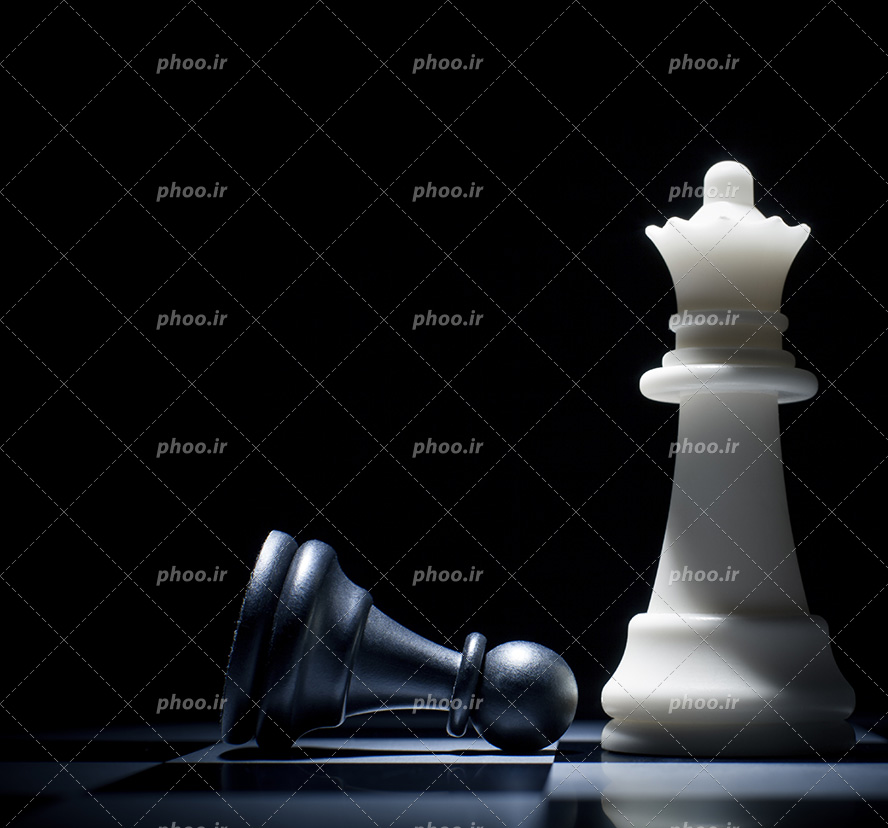 عکس با کیفیت مهره ی شطرنج به رنگ سفید در کنار مهره ی افتاده به رنگ مشکی و قرار گرفته بر روی صفحه شطرنج
