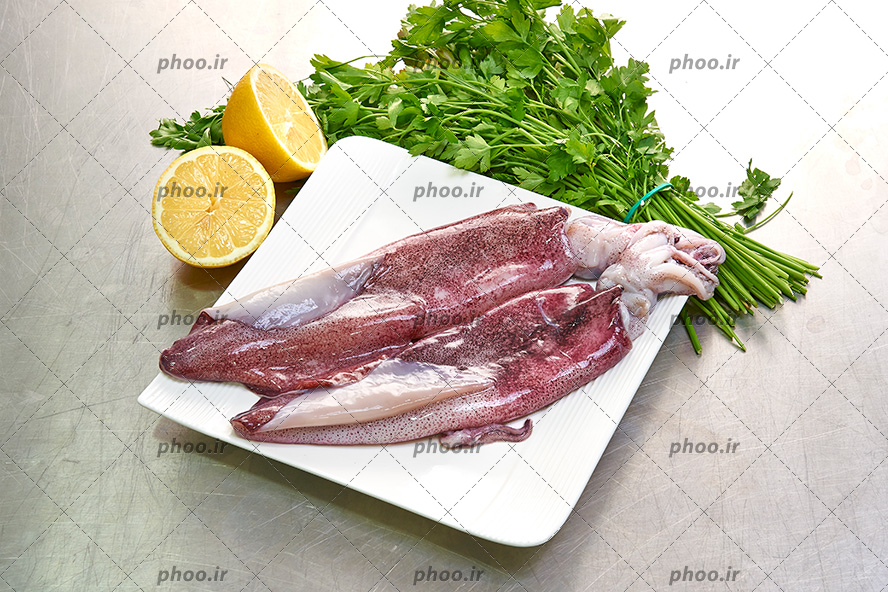 عکس با کیفیت گوشت در ظرف سفید در کنار لیمو ترش و سبزیجات