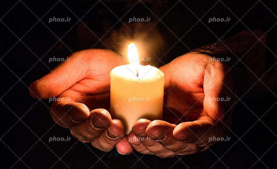عکس با کیفیت شمع روشن در دست مرد در تاریکی مناسب برای عزاداری ها و شهدات ها