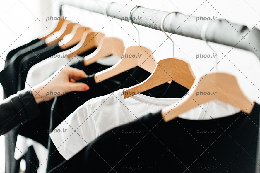 عکس با کیفیت تیشرت های سیاه و سفید در رگال و زن در حال نگاه کردن به آن ها