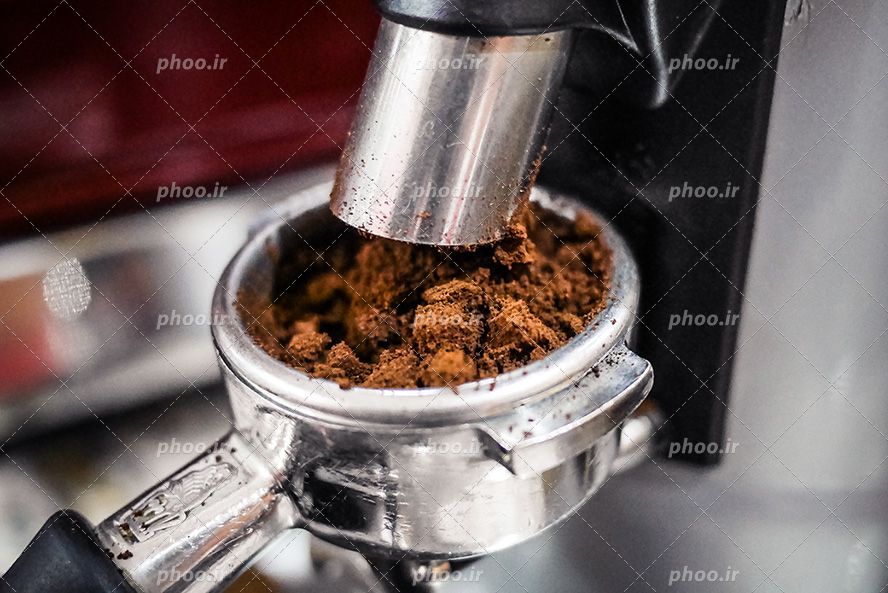 عکس با کیفیت قهوه پودر شده در حال ریختن در دستگاه قهوه ساز