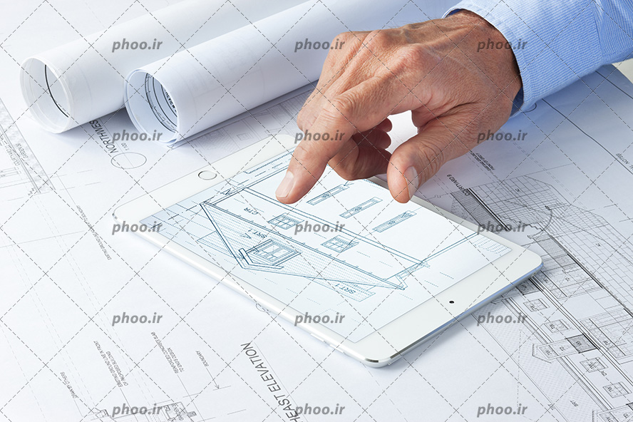 عکس با کیفیت مرد در حال نشان دادن اسکیس خانه در آیپد بر روی نقشه های ساختمان