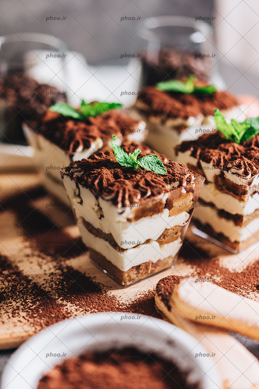 عکس با کیفیت چهار تیرامیسو شکلاتی در کنار یکدیگر چیده شده و تزیین شده با پودر کاکائو و برگ نعناع