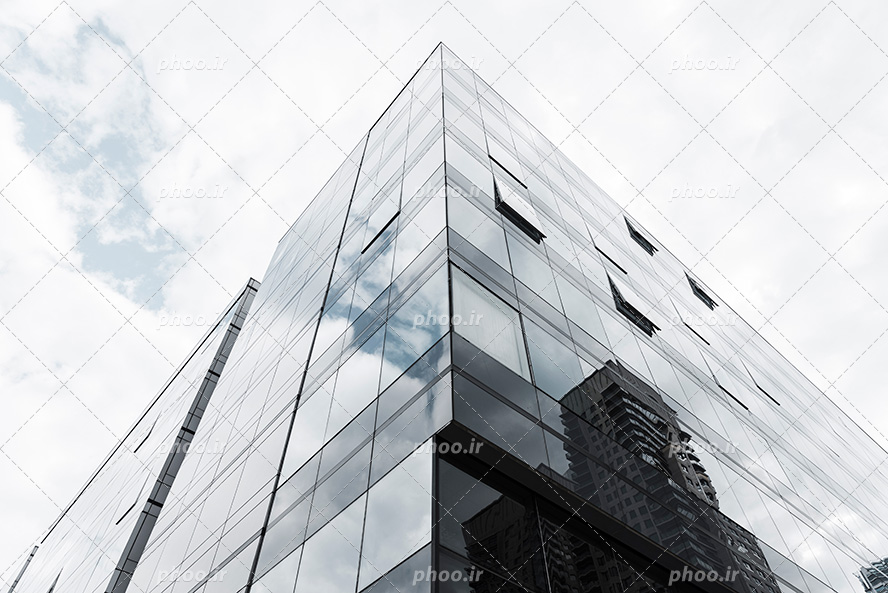 عکس با کیفیت تصویر از زاویه پایین یک ساختمان با شیشه های رفلکس