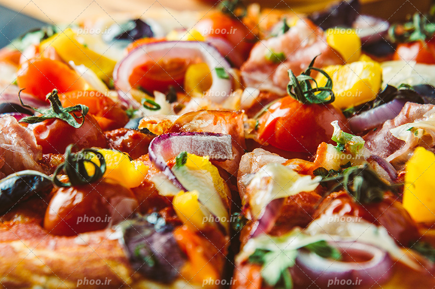 عکس با کیفیت پیتزای سبزیجات با تزئین گوجه و حلقه های پیاز و فلفل دلمه های رنگارنگ