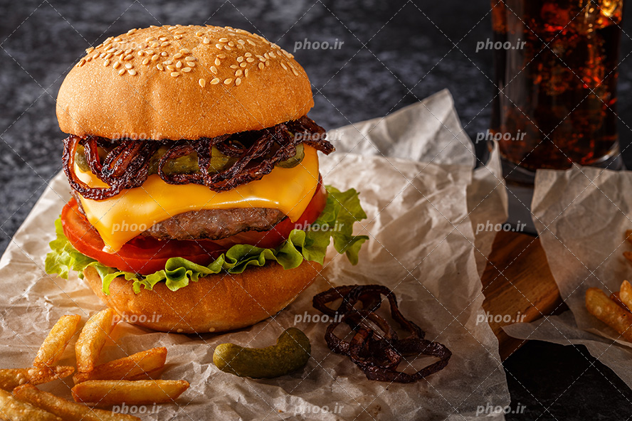عکس با کیفیت سیب زمینی در کنار سانویچ همبرگر پر ملات در کنار لیوان نوشابه