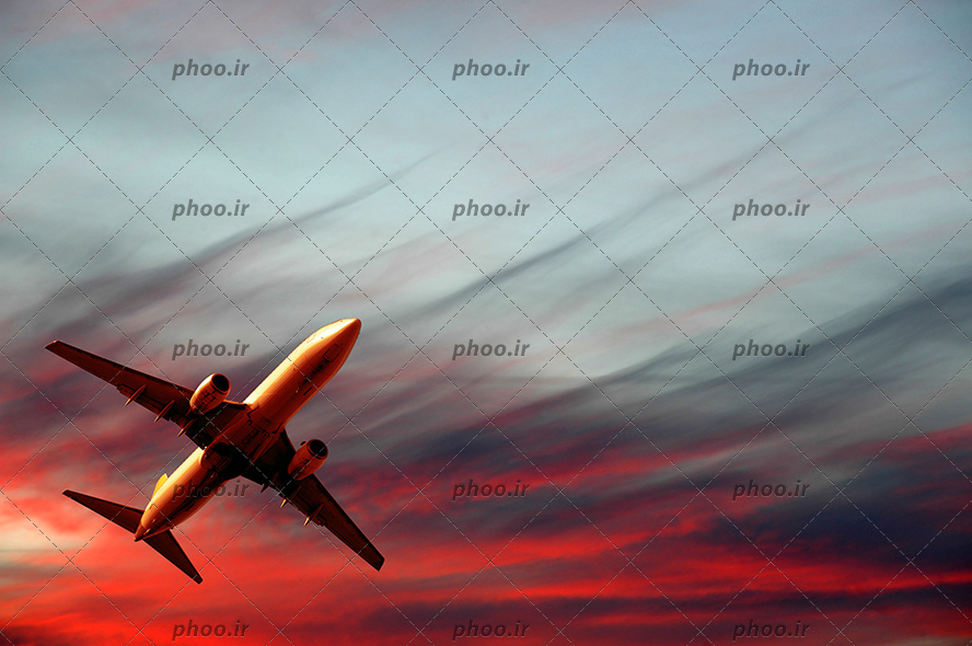 عکس هواپیمای در حال پرواز و دود هایی در آسمان و غروب خورشید