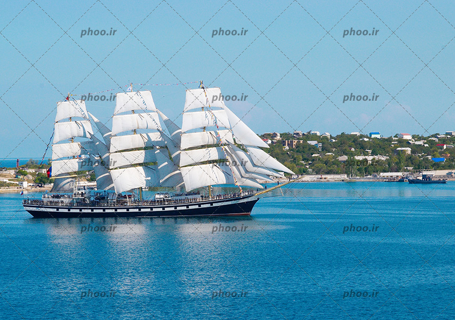 عکس یک کشتی با بادبان های سفید روی دریا آبی