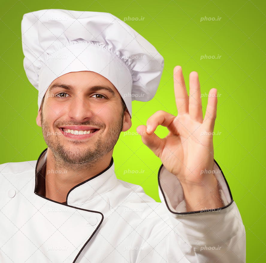 عکس با کیفیت مرد سرآشپز با کلاه و لباس مخصوص در حال نشان دادن علامت عالی و لبخند به لب و پس زمینه به رنگ سبز