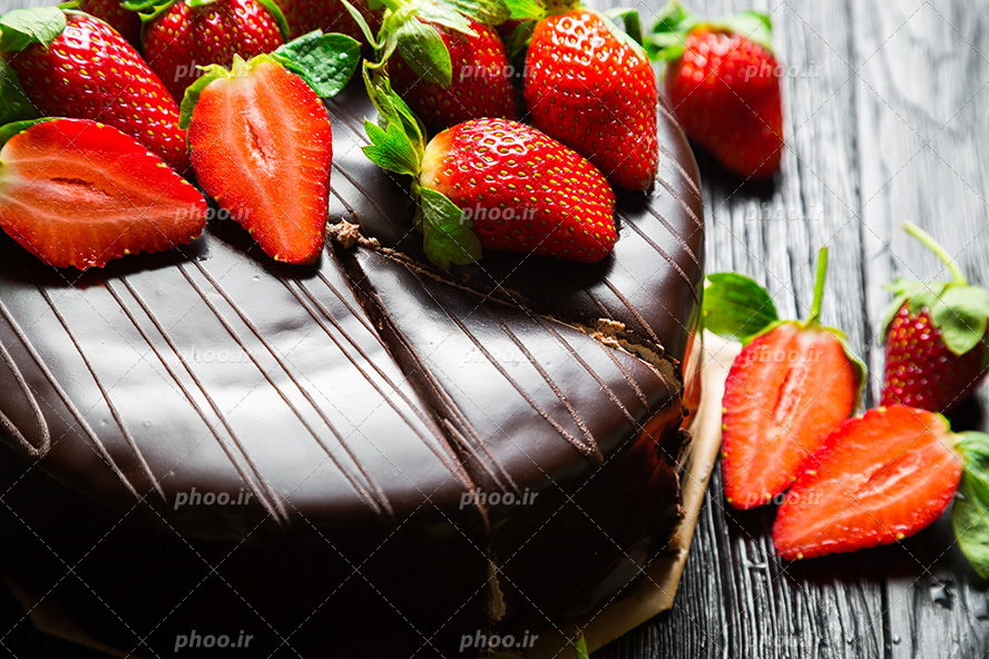 عکس با کیفیت کیک با روکش شکلاتی و تزئین شده با توت فرنگی های خوشمزه