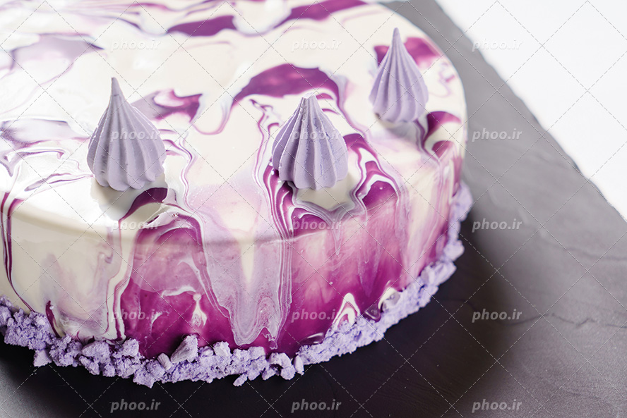 عکس با کیفیت کیک خامه ای تزئین شده با خامه بنفش به شکل ابستره و گل های بنفش بر روی کیک و تزئین دور کیک با شکلات سنگی بنفش