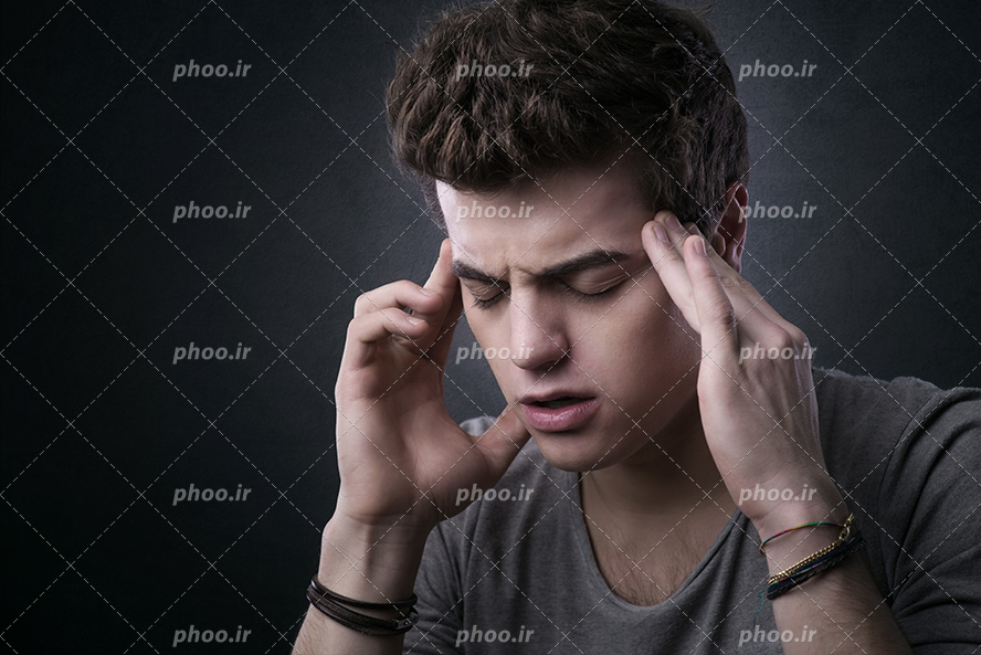 عکس با کیفیت مرد دارای سر درد و در حالت گرفتن سر خود با هر دو دست