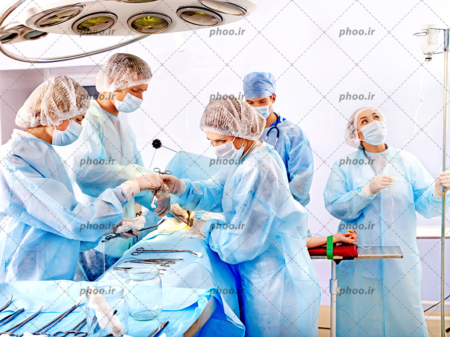 عکس با کیفیت دکتر ها و پرستار با روپوش آبی داخل اتاق عمل در حال جراحی بیمار