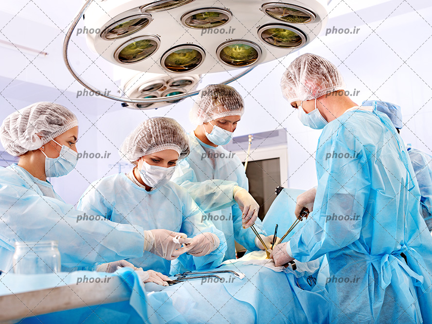 عکس با کیفیت پزشک مرد و زن با روپوش های آبی در حال جراحی بیمار در اتاق عمل