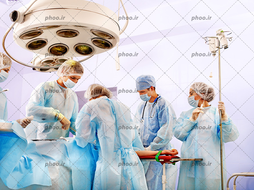 عکس با کیفیت پزشک ها با روپوش های آبی در حال جراحی بیمار در اتاق عمل