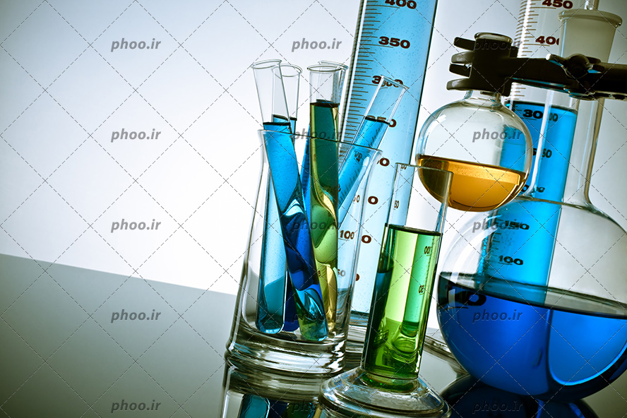 عکس با کیفیت شیشه آلات آزمایشگاهی در ابعاد و اشکال مختلف در کنار یکدیگر و مایعات رنگی در آن ها