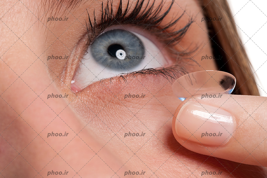 عکس با کیفیت زن با چشم آبی و موژه های بلند در حال گذاشتن لنز طبی بی رنگ