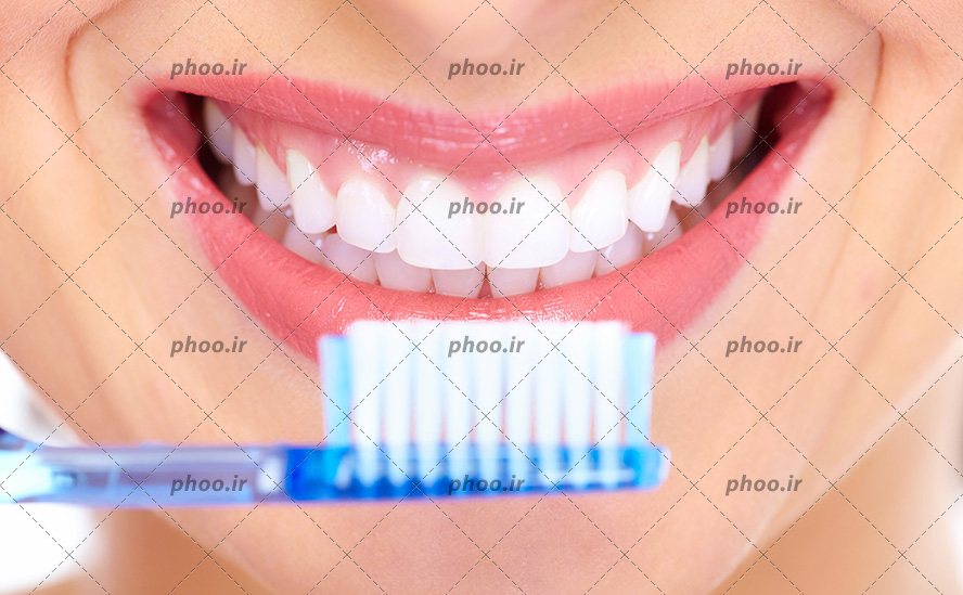 عکس با کیفیت مسواک در مقابل صورت زن و زن در حال لبخند زدن و نشان دادن دندان های سفید و درخشانش