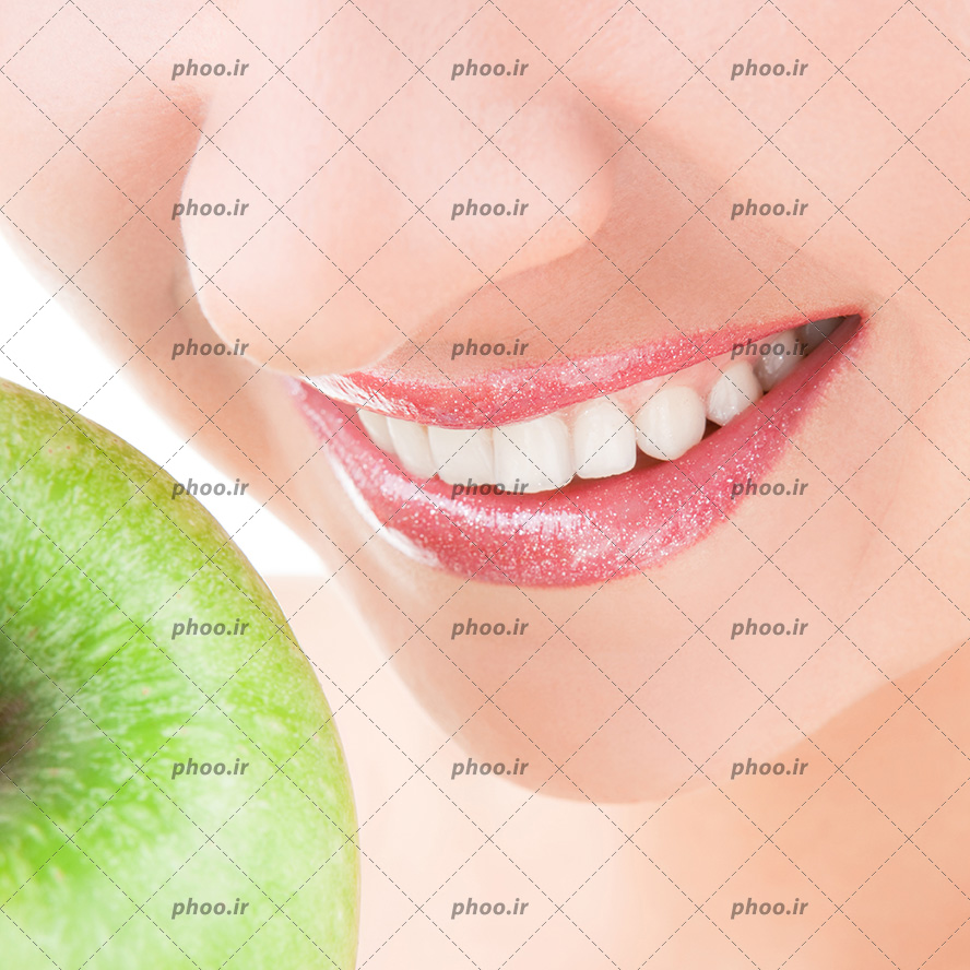 عکس با کیفیت سیب سبز بزرگ در مقابل لب های زن و زن با لبخندی و لب های زیبا و دندان های سفید براق