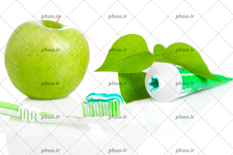 عکس با کیفیت خمیر دندان و مسواک سبز در کنار چند برگ سبز و سیب سبز ترش