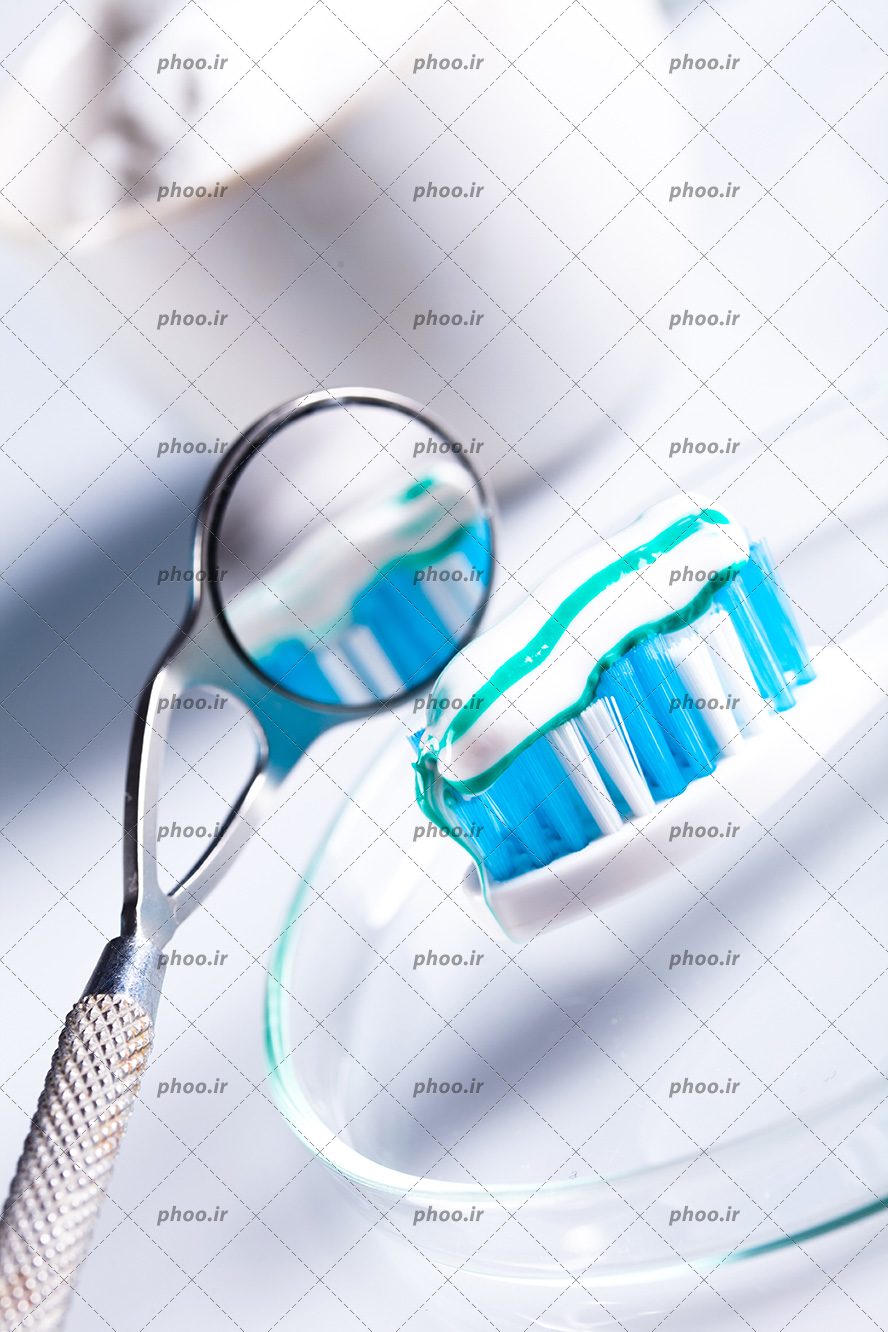 عکس با کیفیت مسواک همراه با خمیر دندان مقابل آینه گرد کوچک دندان پزشکی از نمای نزدیک
