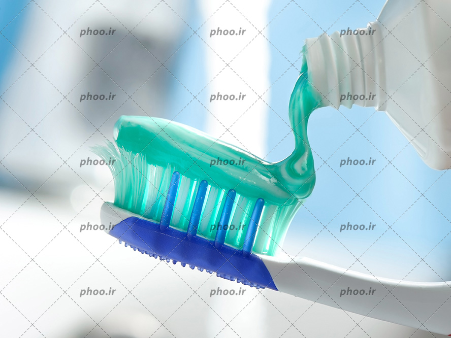 عکس با کیفیت در حال ریختن خمیر دندان بر روی مسواک از نمای نزدیک