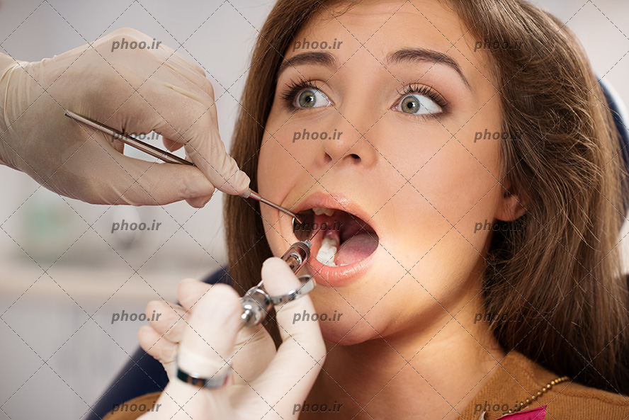 عکس با کیفیت ترس در چشم های بیمار و دندانپزشک در حال آمپول زدن به لثه زن