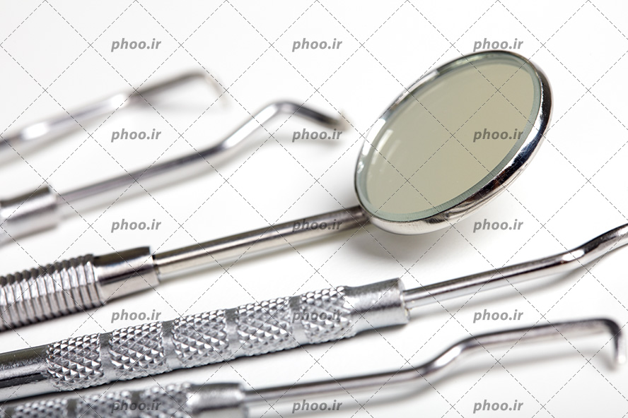 عکس با کیفیت آینه مقعر در کنار ابزار های دندانپزشکی از نمای نزدیک
