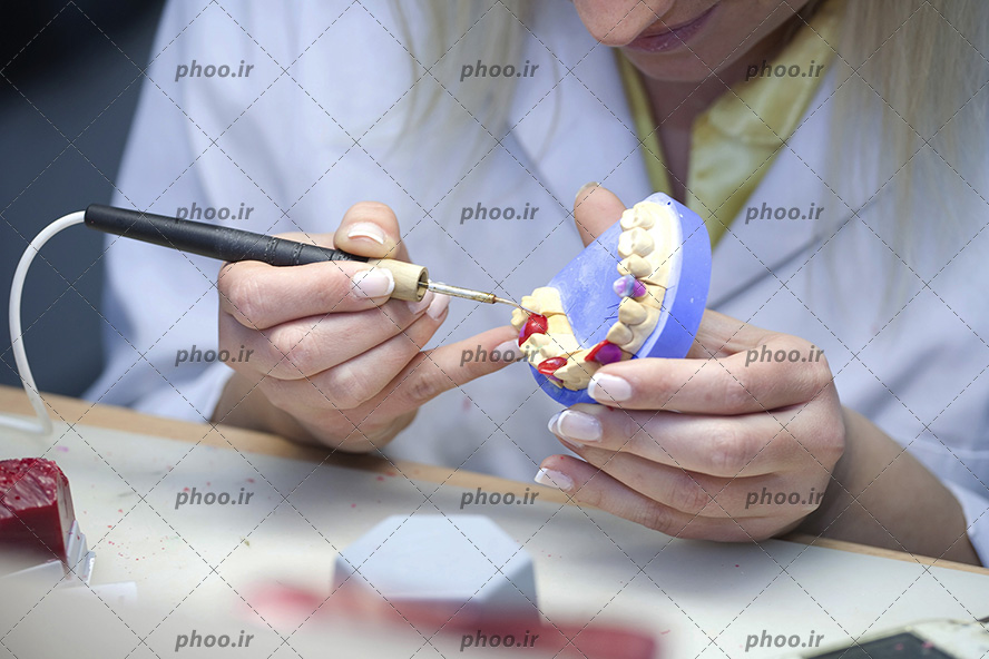 عکس با کیفیت دندانپزشک در حال تمرین پر کردن دندان بر روی ماکت دندان